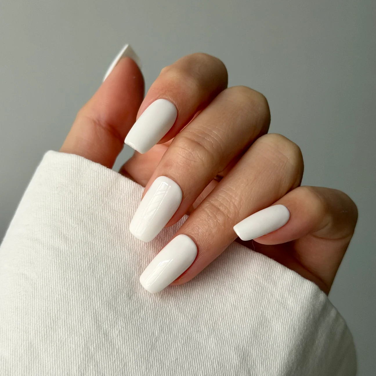 Marshmallow white press-on nails worn on a hand