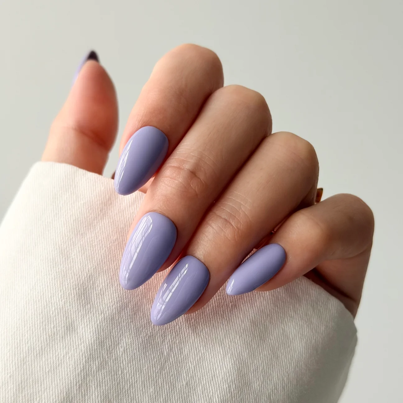 Lavender solid colour press-on nails worn on a hand
