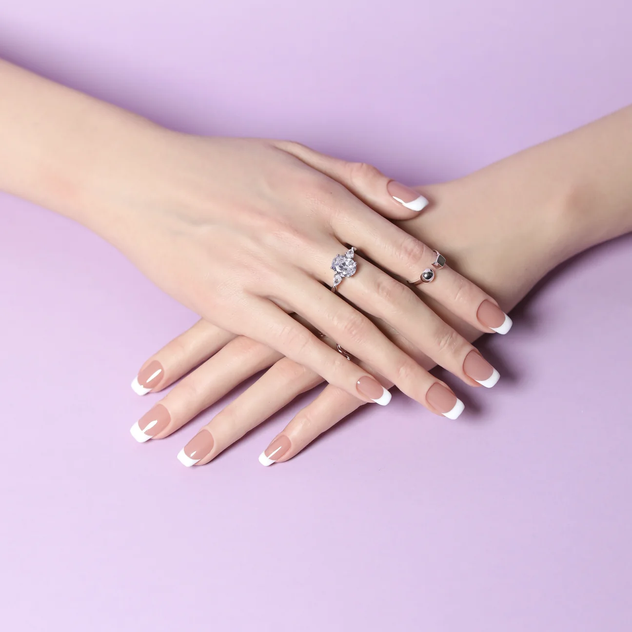 Square French tip press-on nails on crossed hands