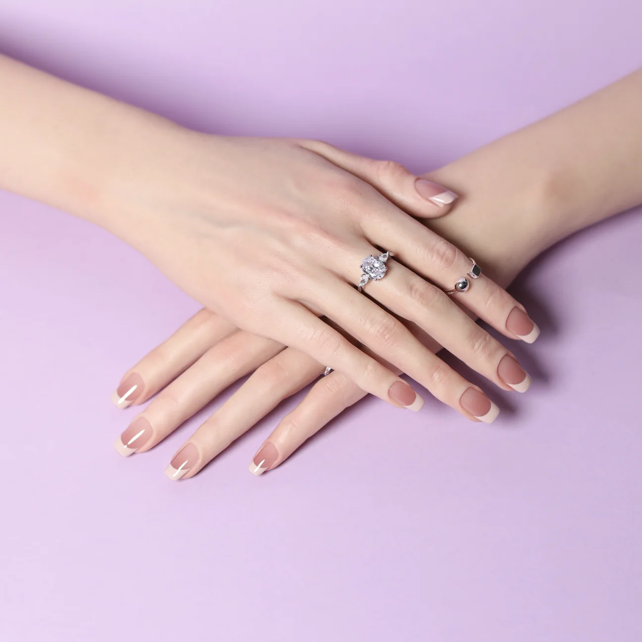 Blush French tip press-on nails on crossed hands