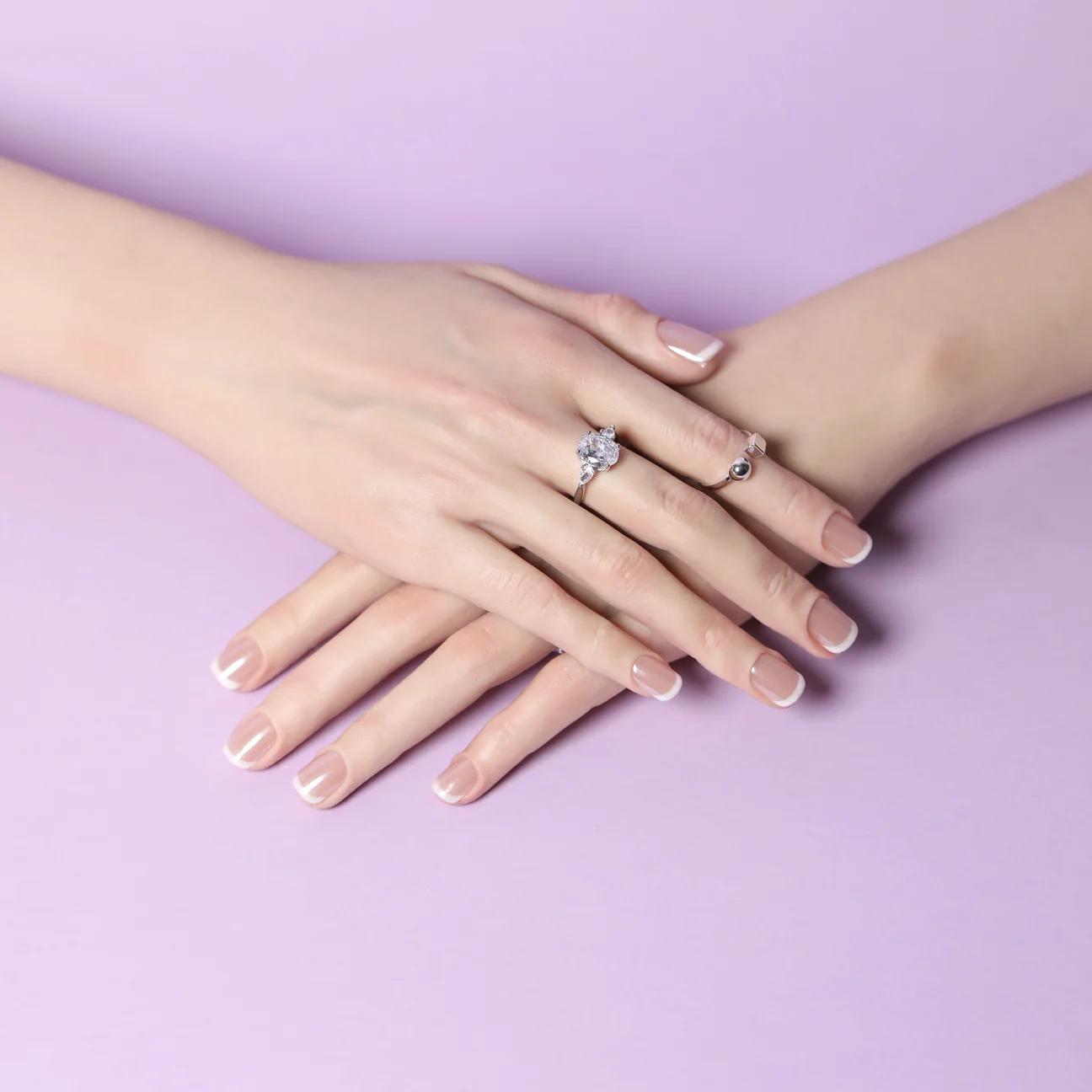 Short French tip press-on nails on crossed hands